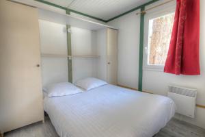 a bedroom with a white bed and a window at Les Chalets du Périgord in Sarlat-la-Canéda