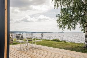 two chairs and a table on a wooden deck with the water at First Camp Orsa - Dalarna in Orsa
