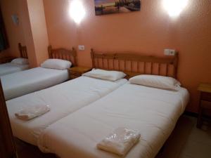 three beds in a room with white sheets at Apartaments Els Avets in Pas de la Casa