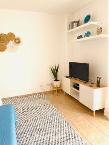 a living room with a flat screen tv on a cabinet at Casa da Boa Gente in Cabanas de Tavira