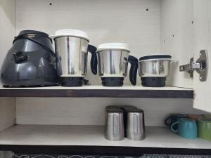a shelf with four pots and pans on it at Homlee-Best Value flat with kitchen Near Metro in New Delhi