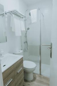 y baño blanco con aseo y ducha. en Texeda Room Suites en Tejeda
