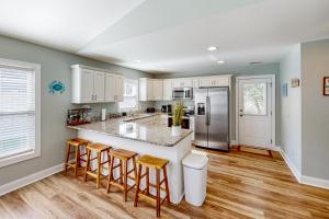 a kitchen with white cabinets and a island with bar stools at Oak Island Oasis in Oak Island