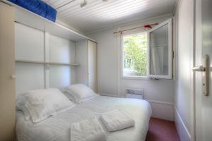 a small bedroom with a white bed and a window at Les Chalets du Périgord in Sarlat-la-Canéda