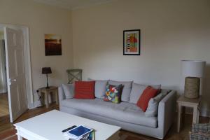 uma sala de estar com um sofá cinzento com almofadas vermelhas em Oldwood. Fyvie. em Turriff