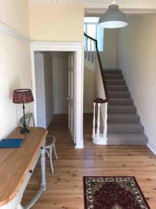 a living room with a staircase and a table with a lamp at Oldwood. Fyvie. in Turriff