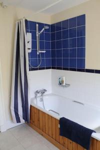 y baño con bañera, ducha y azulejos azules. en Oldwood. Fyvie., en Turriff
