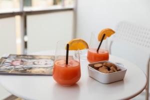 einen Tisch mit zwei Cocktails und einer Schüssel Essen in der Unterkunft La Hara Apartments in Neapel