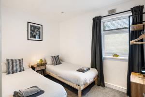 two beds in a room with a window at Apartment Nr City Centre & Park For up to 6 in Cardiff