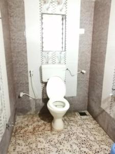 La salle de bains est pourvue de toilettes blanches et d'une fenêtre. dans l'établissement Acharekar's Home stay - Adorable AC and Non AC Rooms with free Wi-Fi, à Malvan