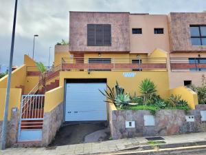 una casa amarilla con una puerta de garaje azul en Los Briones, en Puerto de la Cruz