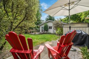 a group of red chairs and an umbrella on a deck at West and Relaxation - Greytown Holiday Home in Greytown