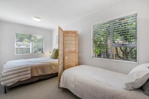 a bedroom with two beds and two windows at West and Relaxation - Greytown Holiday Home in Greytown