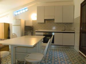 a kitchen with white cabinets and a table and chairs at Attico cavo a pochi passi dal mare in Cavo