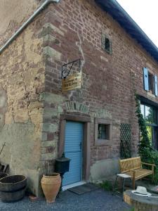 um edifício de tijolos com uma porta azul e um banco em La Grange de Bois de Chêne em Phalsbourg