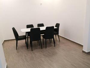 een eettafel met zwarte stoelen en een witte muur bij Chris Cozyplace in Bayan Lepas