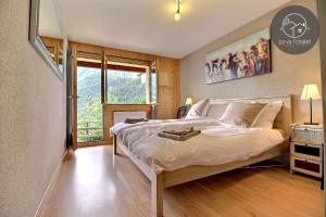 a bedroom with a large bed and a large window at Chalet Arwi in Ovronnaz