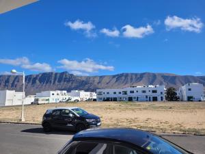 two cars parked in a parking lot with mountains in the background at ISLOTE in Famara
