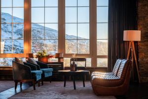 uma sala de estar com cadeiras, uma mesa e janelas em The Mountains Hotel em Sierra Nevada