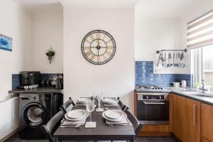 a kitchen with a table and a clock on the wall at Charming Terraced House in Central Hoylake in Hoylake