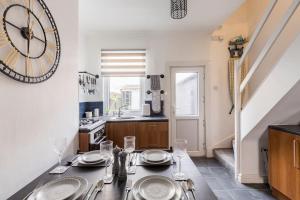 een keuken met een tafel en een klok aan de muur bij Charming Terraced House in Central Hoylake in Hoylake