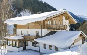 une maison dans la neige avec des toits recouverts de neige dans l'établissement Haus Spieleck, à Saalbach-Hinterglemm