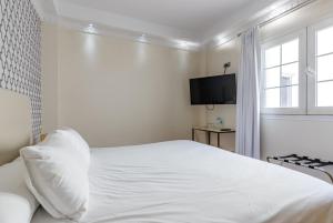 Habitación blanca con cama y TV en H-A Hotel Trebol, en Málaga