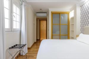 um quarto com uma cama branca e uma janela em H-A Hotel Trebol em Málaga