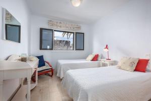 a white room with two beds and a window at Casa La Malondra in Puerto del Carmen