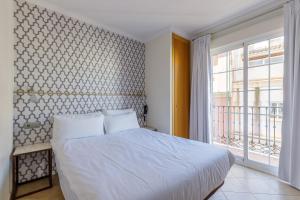 - une chambre avec un lit et une grande fenêtre dans l'établissement H-A Hotel Trebol, à Malaga