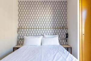 1 dormitorio con 2 almohadas blancas en H-A Hotel Trebol, en Málaga