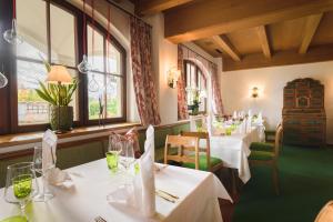 restauracja z białymi stołami, krzesłami i oknami w obiekcie Hotel Gasthof Brandstätter w mieście Salzburg