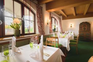 a restaurant with white tables and chairs and windows at Hotel Gasthof Brandstätter in Salzburg