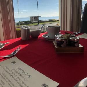 a table with a red table cloth and a plate of food at Swn Y Mor in Llandudno