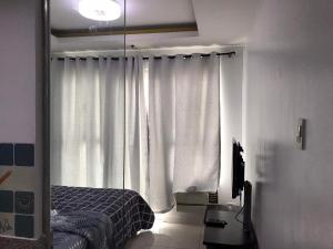 a bedroom with a bed and a window with curtains at Birch tower by matthqueenroom, malate in Manila