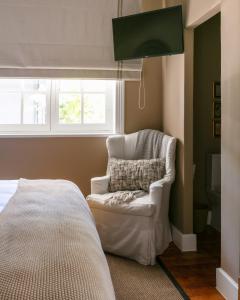 Una silla blanca en una habitación con ventana en The Belmont, en Franschhoek