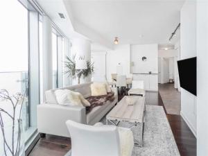 a white living room with a couch and a table at Luxury Condo in the Heart of Toronto - Next to Scotiabank Arena in Toronto