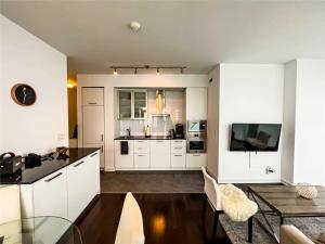 a kitchen and living room with white cabinets and a table at Luxury Condo in the Heart of Toronto - Next to Scotiabank Arena in Toronto