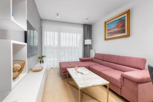 salon z różową kanapą i stołem w obiekcie Westin House Resort Apartment Kołobrzeg by Renters w Kołobrzegu