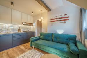 a living room with a blue couch and a kitchen at Izerskie Oblicze in Świeradów-Zdrój