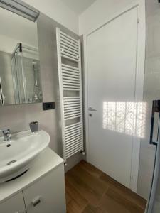 a white bathroom with a sink and a mirror at La corte di Bacco in Maniago