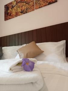 una cama blanca con una toalla y una flor morada en ella en COWORX Koh Lanta, en Ban Mo Nae
