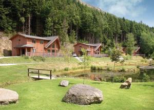 a house on a hill with a pond and some rocks at Penvale Lakes Lodges in Llangollen