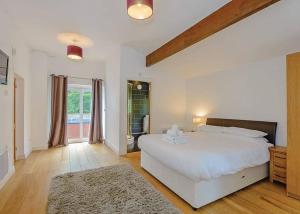 a white bedroom with a large bed and a window at Penvale Lakes Lodges in Llangollen