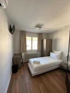 a bedroom with a white bed and a window at Hôtel Le Costellan in Dagneux