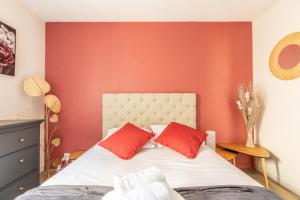 um quarto com paredes vermelhas e uma cama com almofadas vermelhas em L'adorable Confort & Central em Clermont-Ferrand