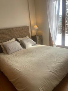a bedroom with a large white bed with a window at APARTAMENT LA MOLINA ( ELS CIRERES ) in Alp