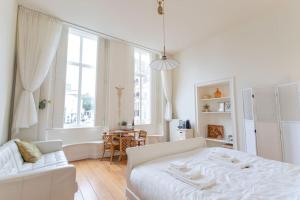 a white bedroom with a white bed and a table at De Dekenije in Zutphen