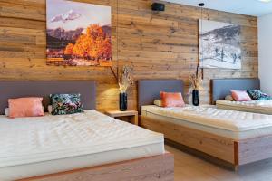 two beds in a room with wooden walls at Mountain Hotel Luis in Kaprun
