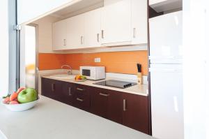 una cocina con armarios blancos y un bol de fruta en Apartamentos Turisticos Rent Guardamar, en Guardamar del Segura